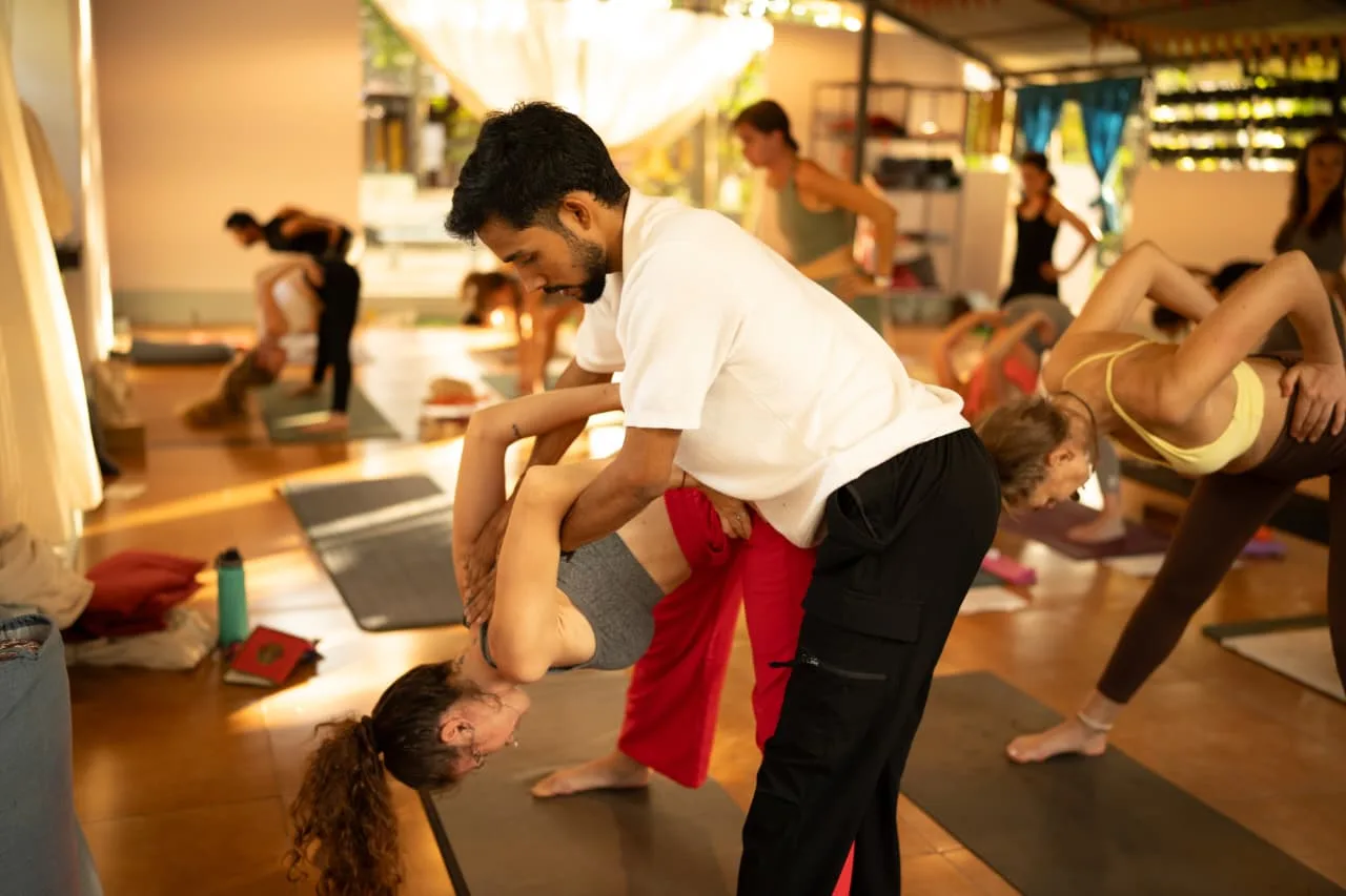 Abhi Nautiyal guiding a student through a yoga adjustment