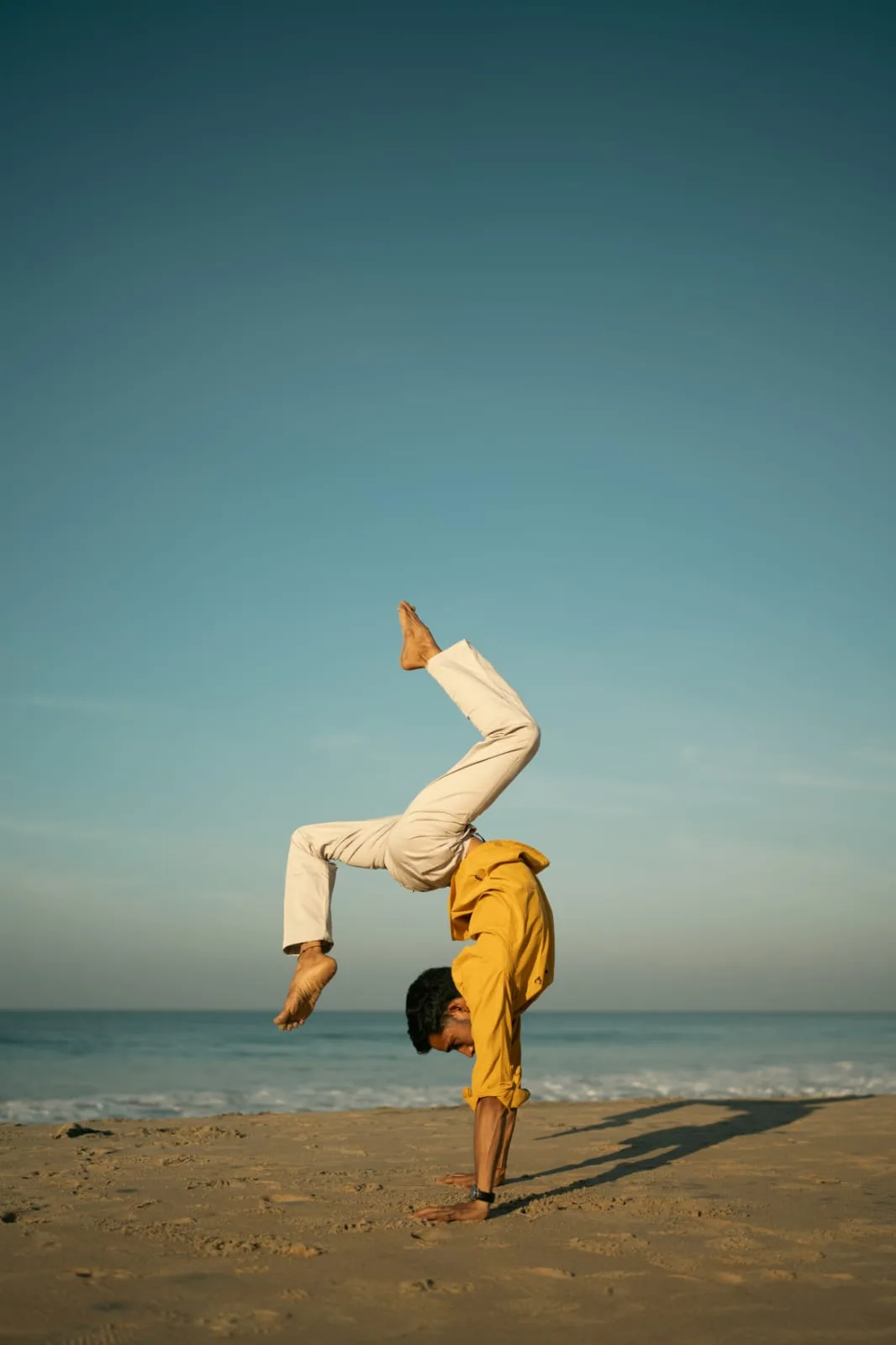 Abhi Nautiyal demonstrating a handstand variation on the beach