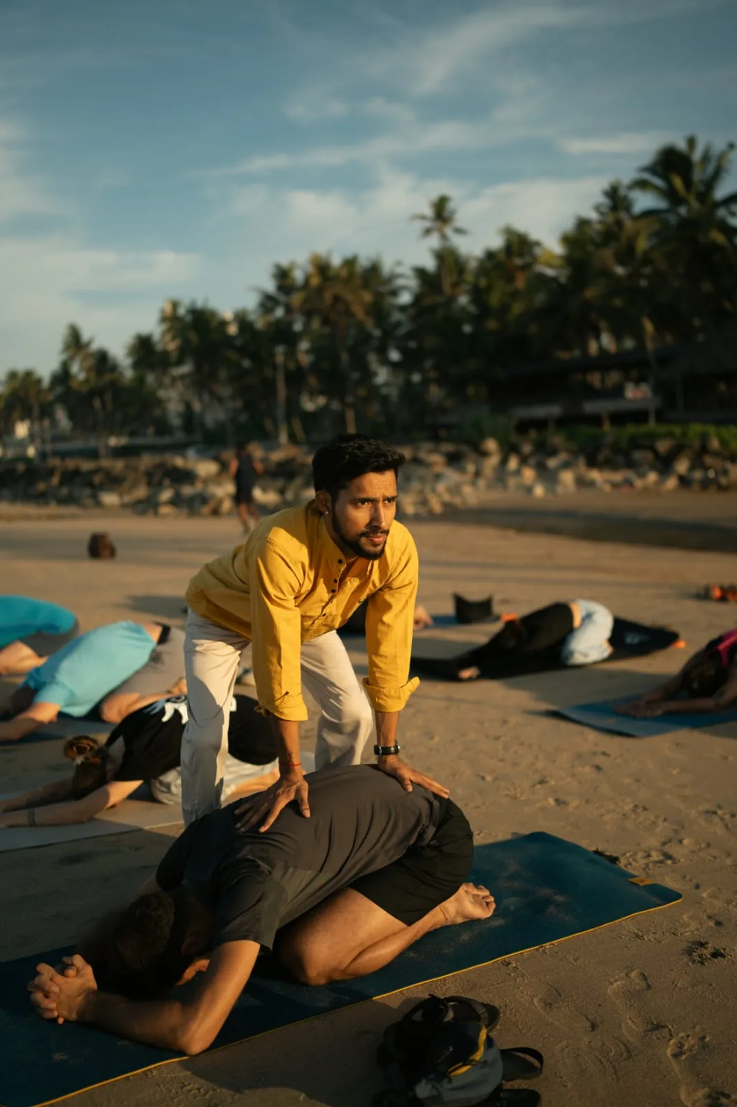 Abhi Nautiyal assisting a student during an outdoor yoga class