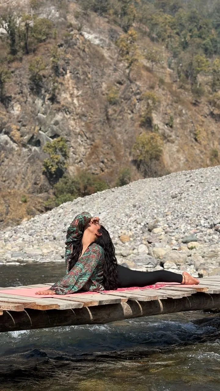 Saloni Chauhan practising yoga on a riverside platform